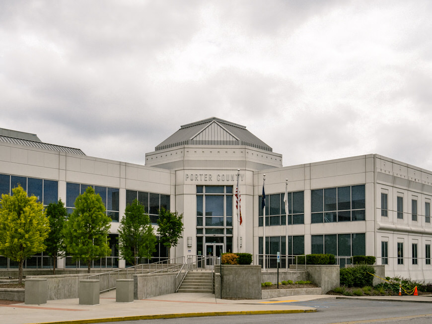 A white building with a lot of trees in front of it.