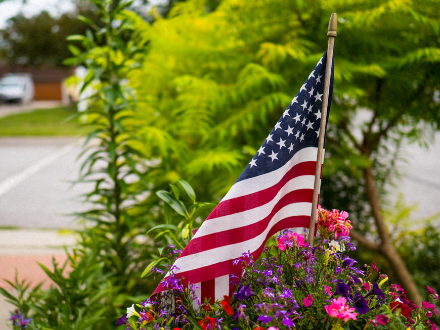 An american flag in a flower bed.