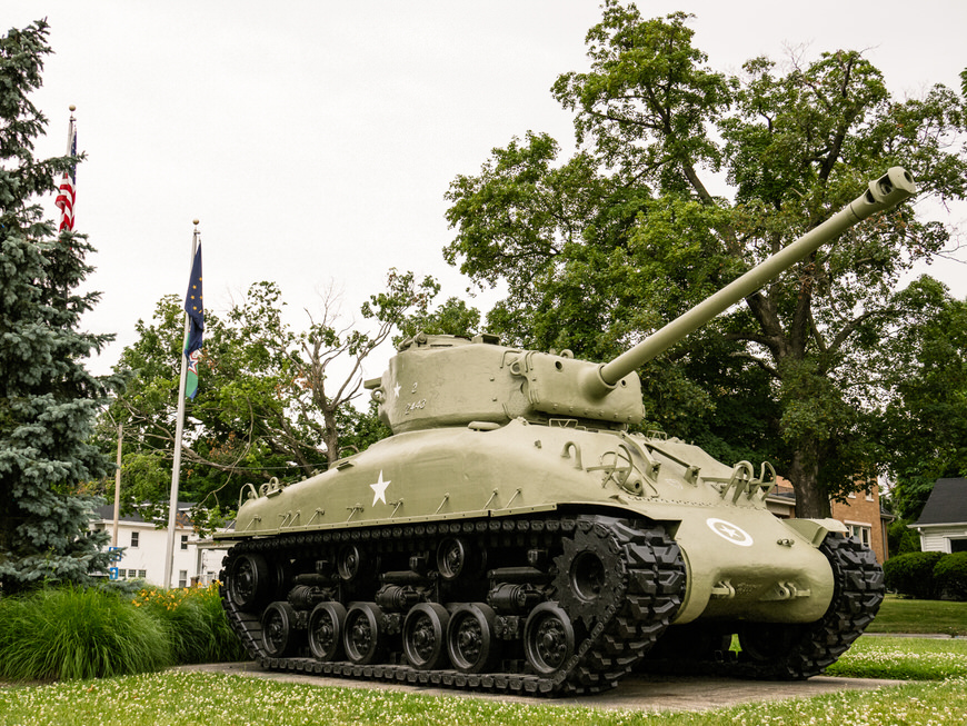 A tank is on display in front of a tree.