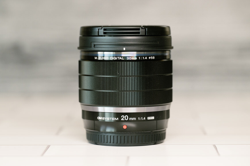 A black camera lens sitting on a tiled floor.