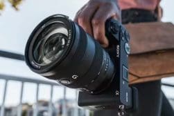 A person holding a camera with a lens attached to it.