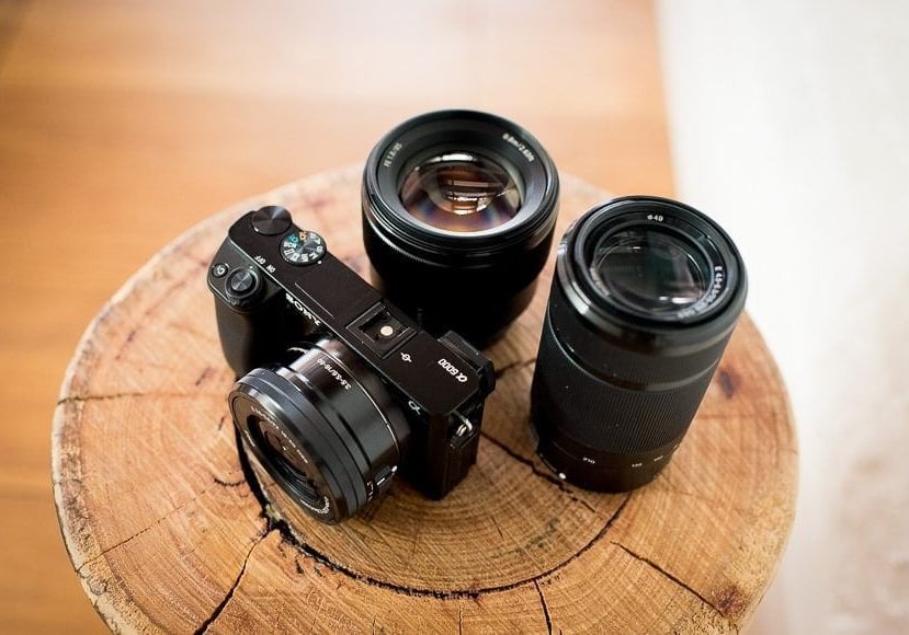 sony a6000 surrounded by lenses on a wooden post