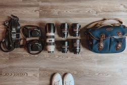 A woman's feet lay on a wooden floor with various camera equipment.