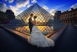 A bride and groom standing in front of a pyramid at sunset.