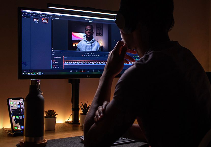 youtube-video-editor a man sitting in front of a computer monitor editing youtube videos.