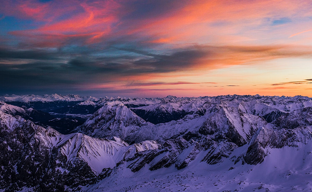 A colorful sunset over snow covered mountains.